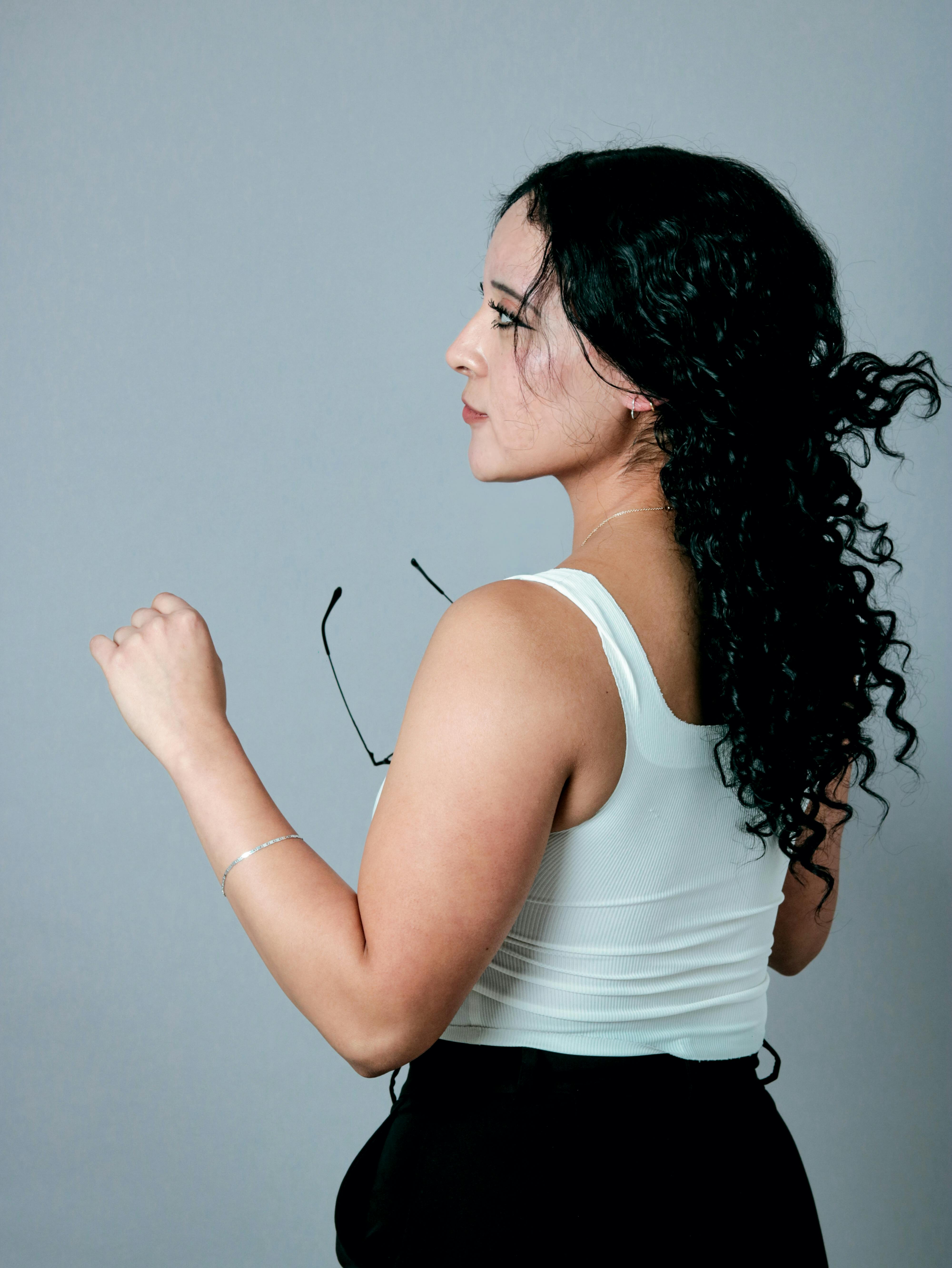 gratis Zijprofiel van een vrouw met krullend haar, gekleed in een witte top, binnen gefotografeerd. Stockfoto