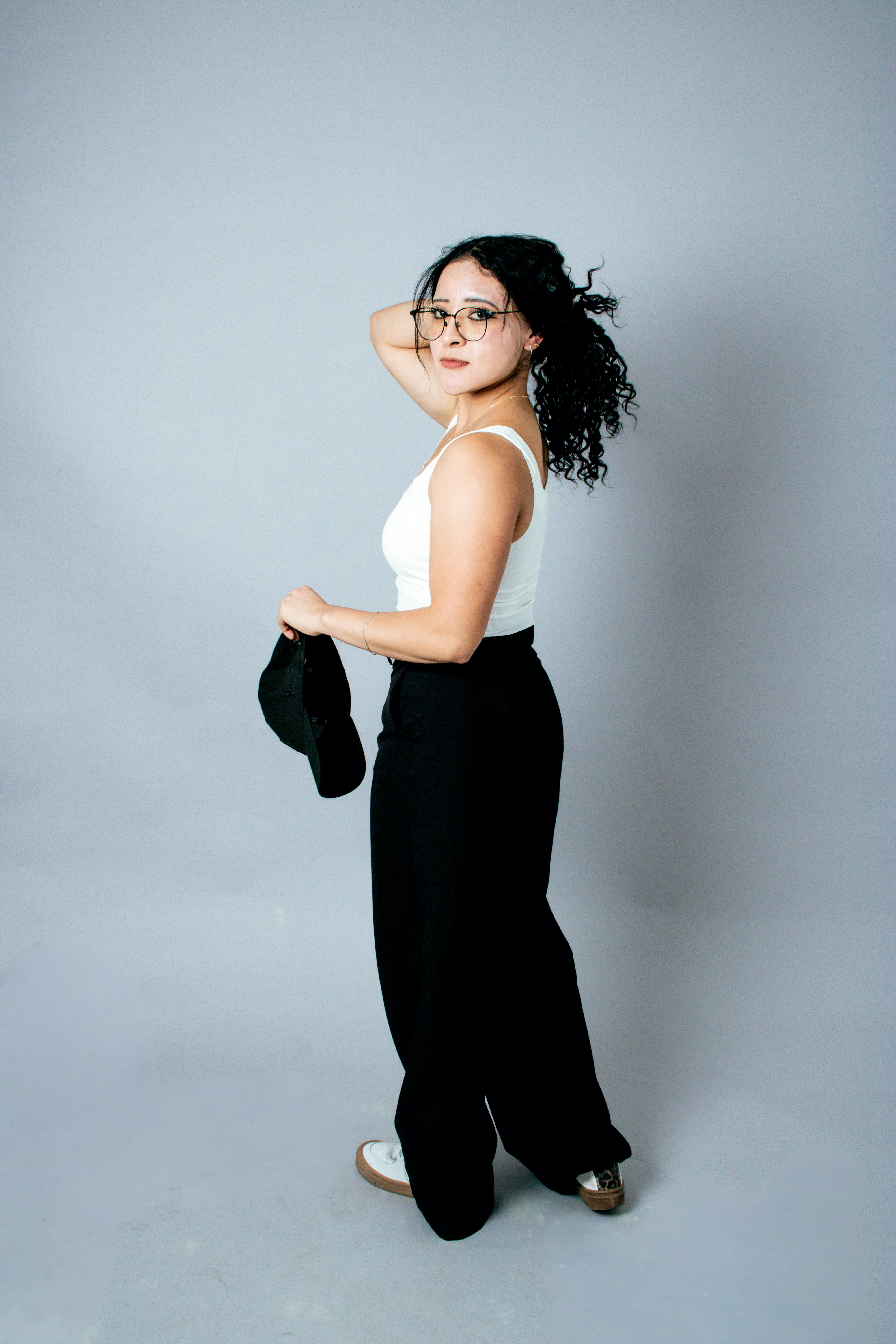 ฟรี หญิงสาวผมหยิกสวมแว่นตาโพสท่าอย่างมีสไตล์ในสตูดิโอถ่ายภาพ คลังภาพถ่าย