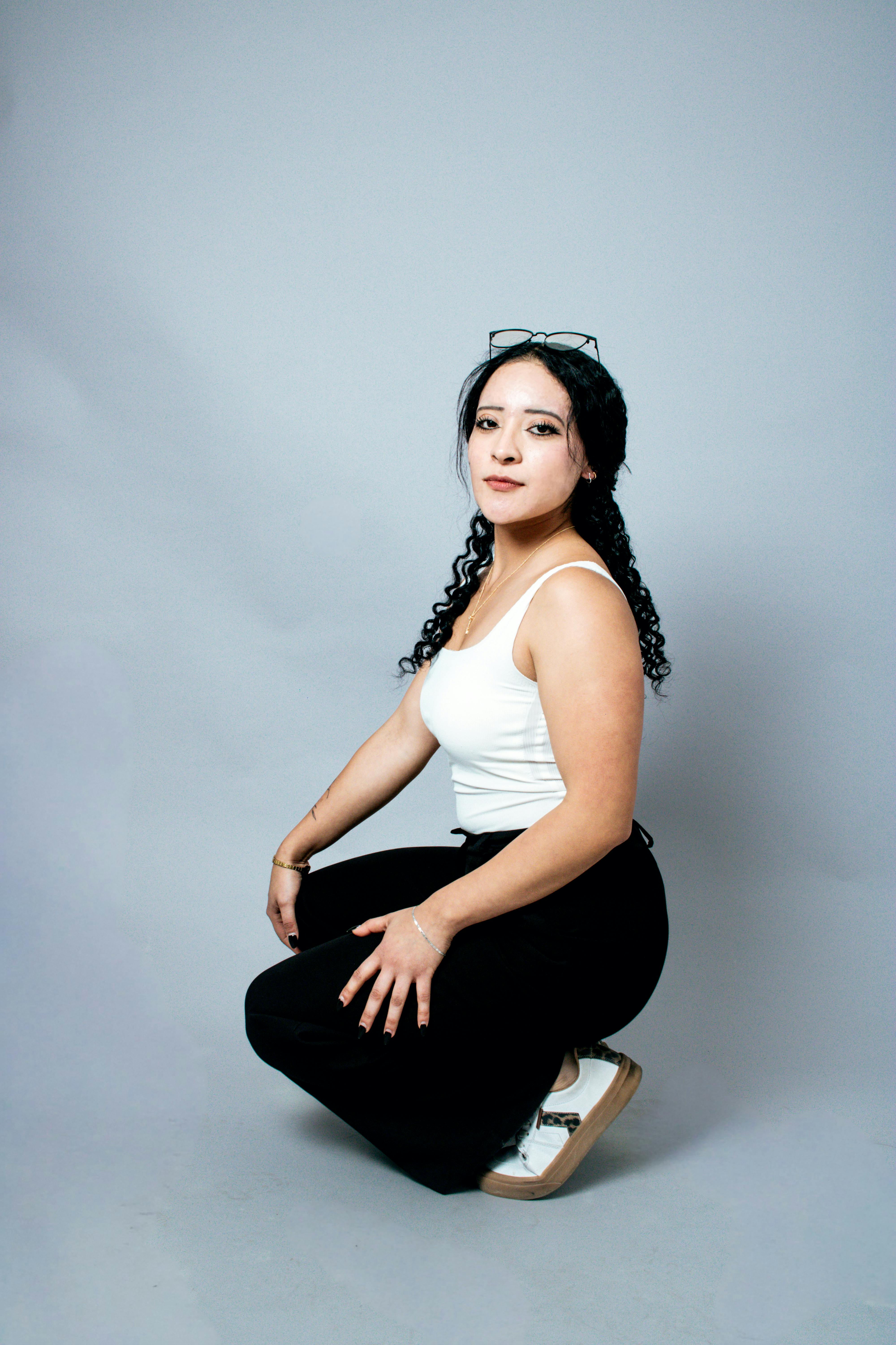Confident young woman with curly hair posing in a studio setting, exemplifying casual style and self-assurance.