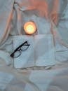 Cozy Reading Scene with Book, Glasses, and Candlelight