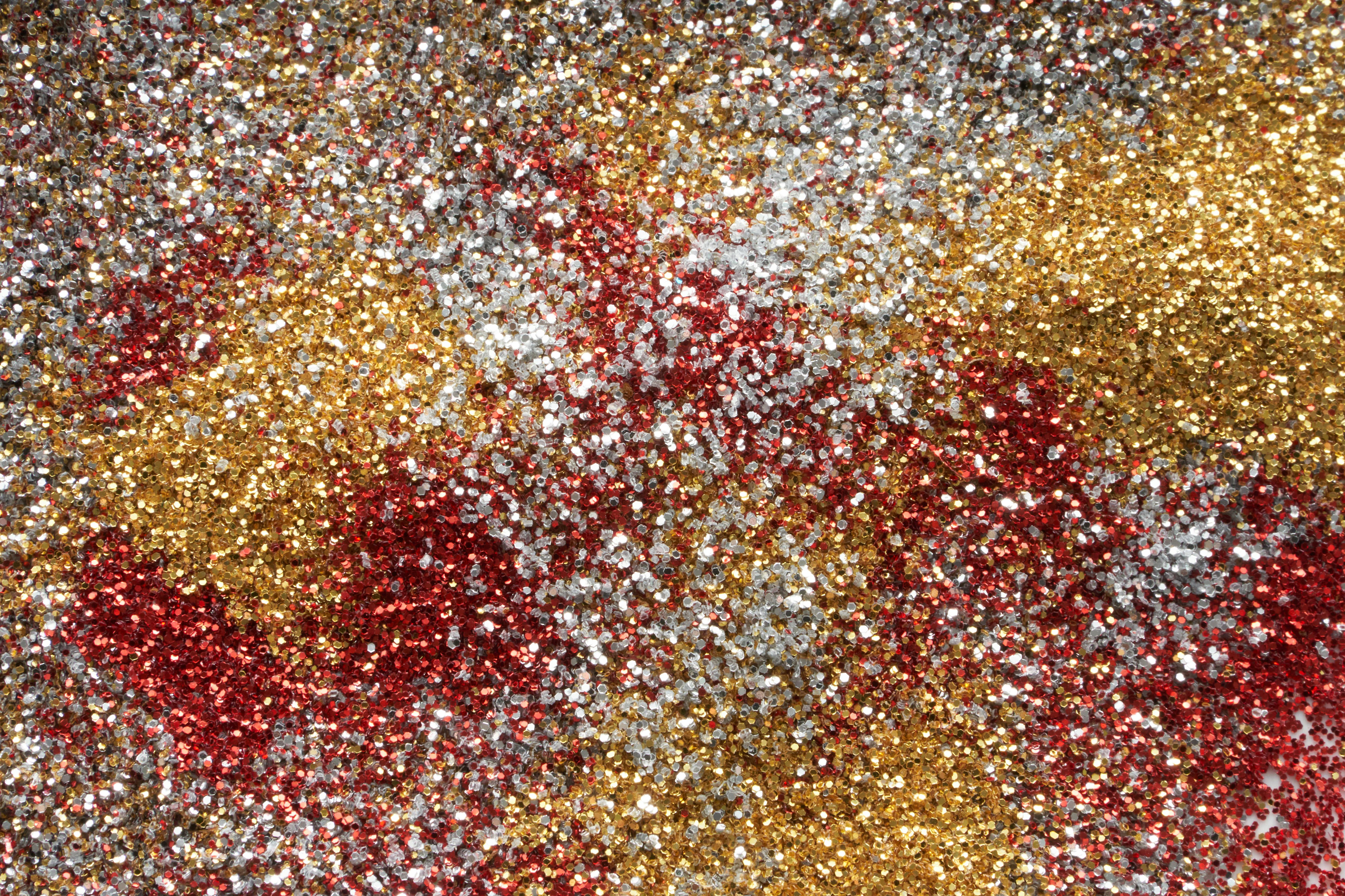 Δωρεάν Ζωντανό μείγμα από κόκκινο, χρυσό και ασημί γκλίτερ που δημιουργεί ένα λαμπερό αφηρημένο φόντο. Φωτογραφία από στοκ φωτογραφιών