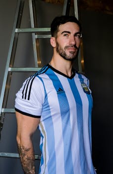 Man wearing Argentina football jersey smiling indoors, casual setting.