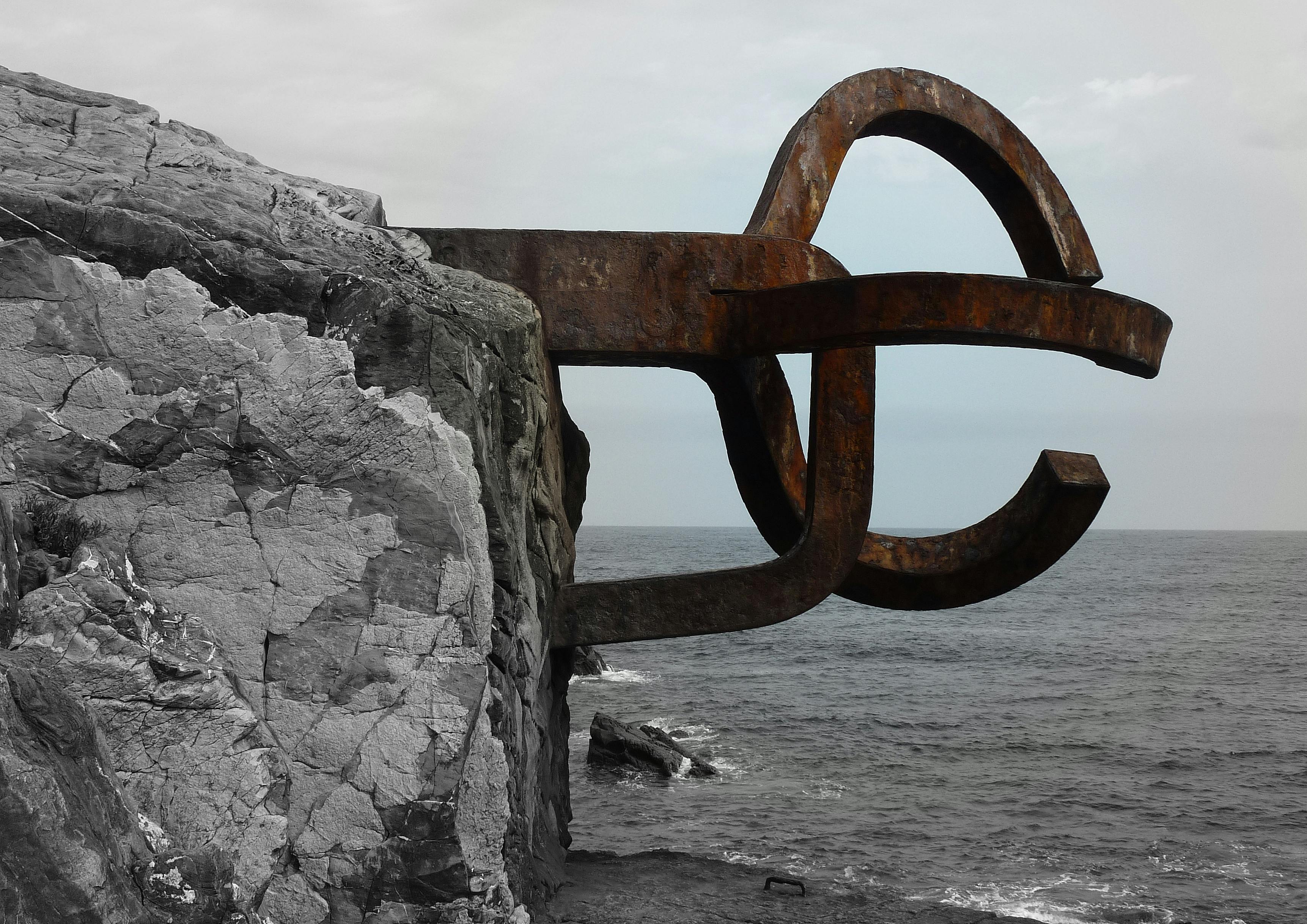 Безкоштовне Іржава металева скульптура на скелястому узбережжі Сан-Себастьяна, Іспанія, на тлі океану. стокове фото