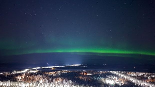 Stunning view of the Northern Lights illuminating a snowy forest in Finland.