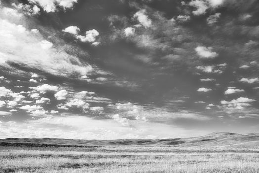 Stunning black and white landscape with dramatic clouds and rolling hills.