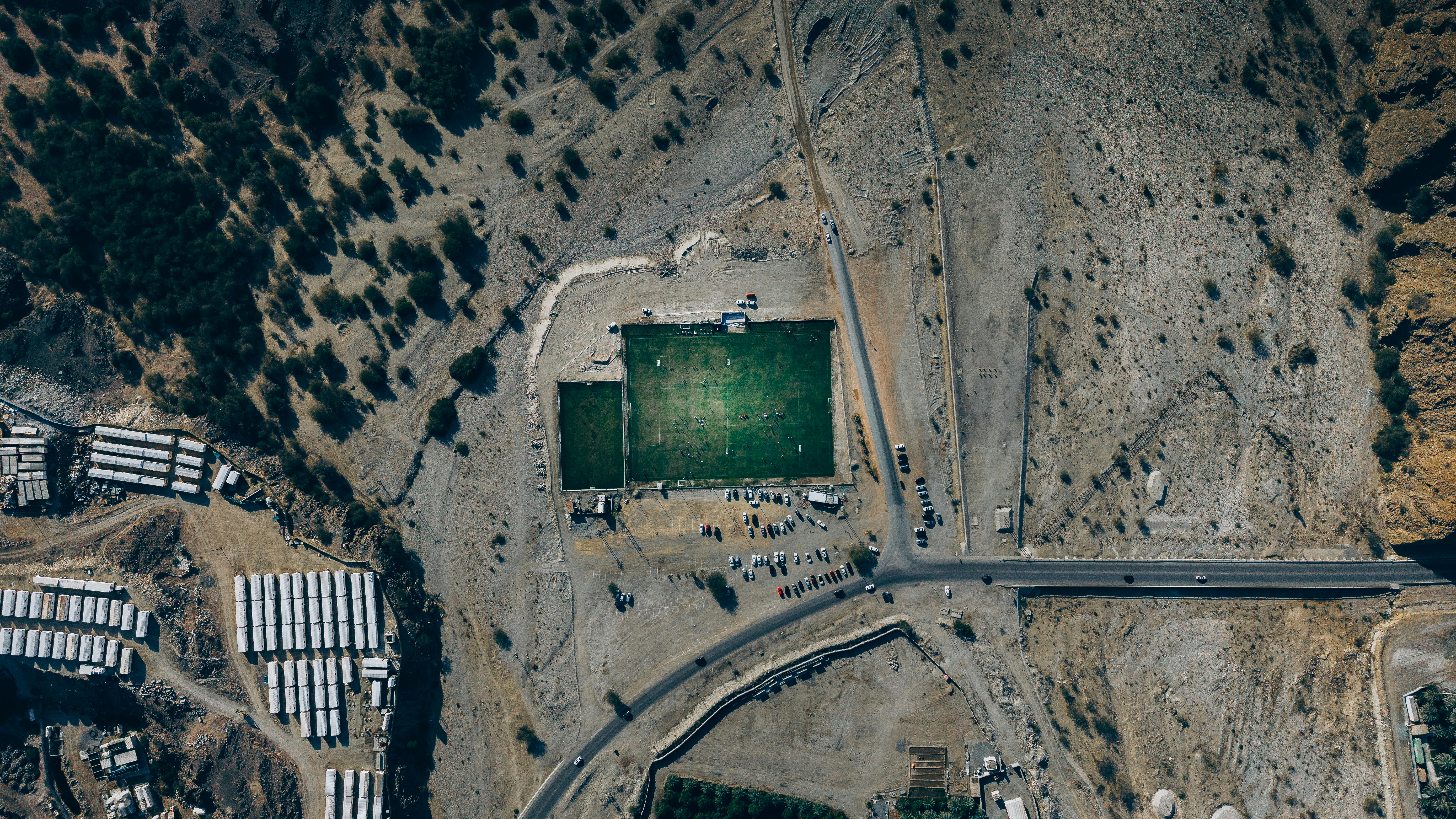 Gratis Rekaman drone lapangan sepak bola di tengah gurun di Oman, menampilkan lanskap yang terjal dan fasilitas olahraga pedesaan. Foto Stok