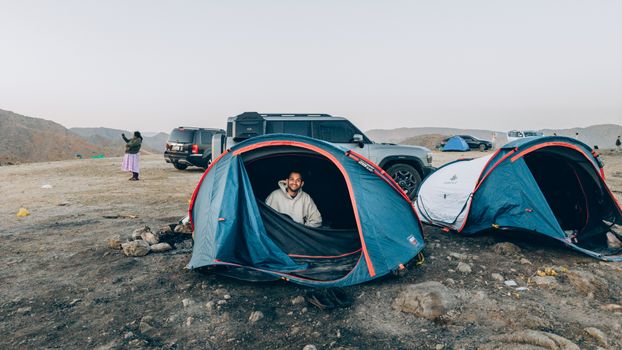 Experience a thrilling camping adventure in Oman's scenic mountains with tents and off-road vehicles.