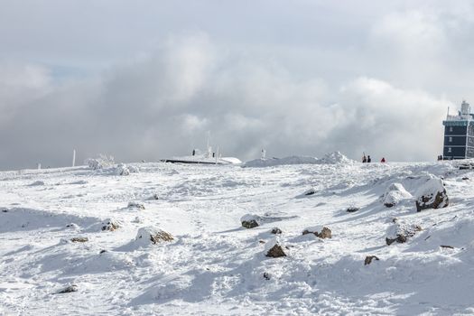 Expansive snowy view on Mount Brocken with clear skies and ice formations.