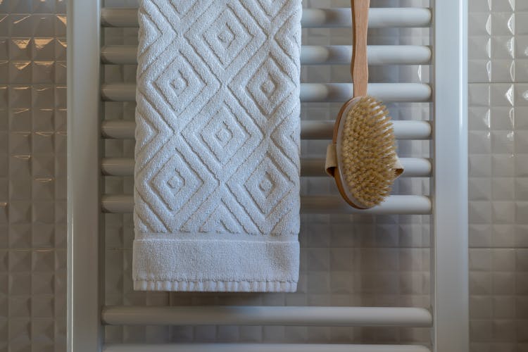 White Towel And Wooden Brush Hanging In The Bathroom