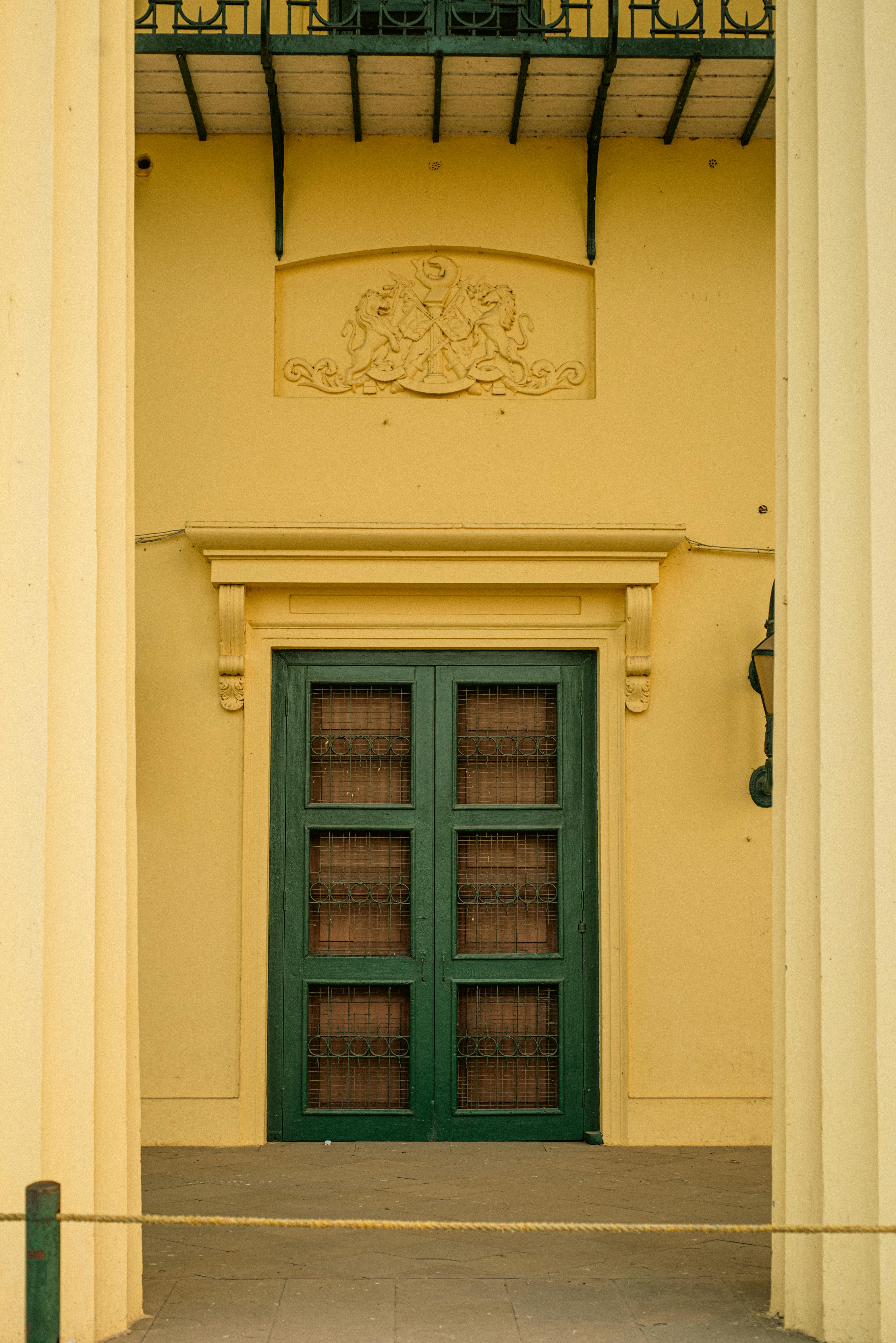 gratis Een esthetische weergave van de ingang van een historisch gebouw met een groene deur en sierlijke details. Stockfoto