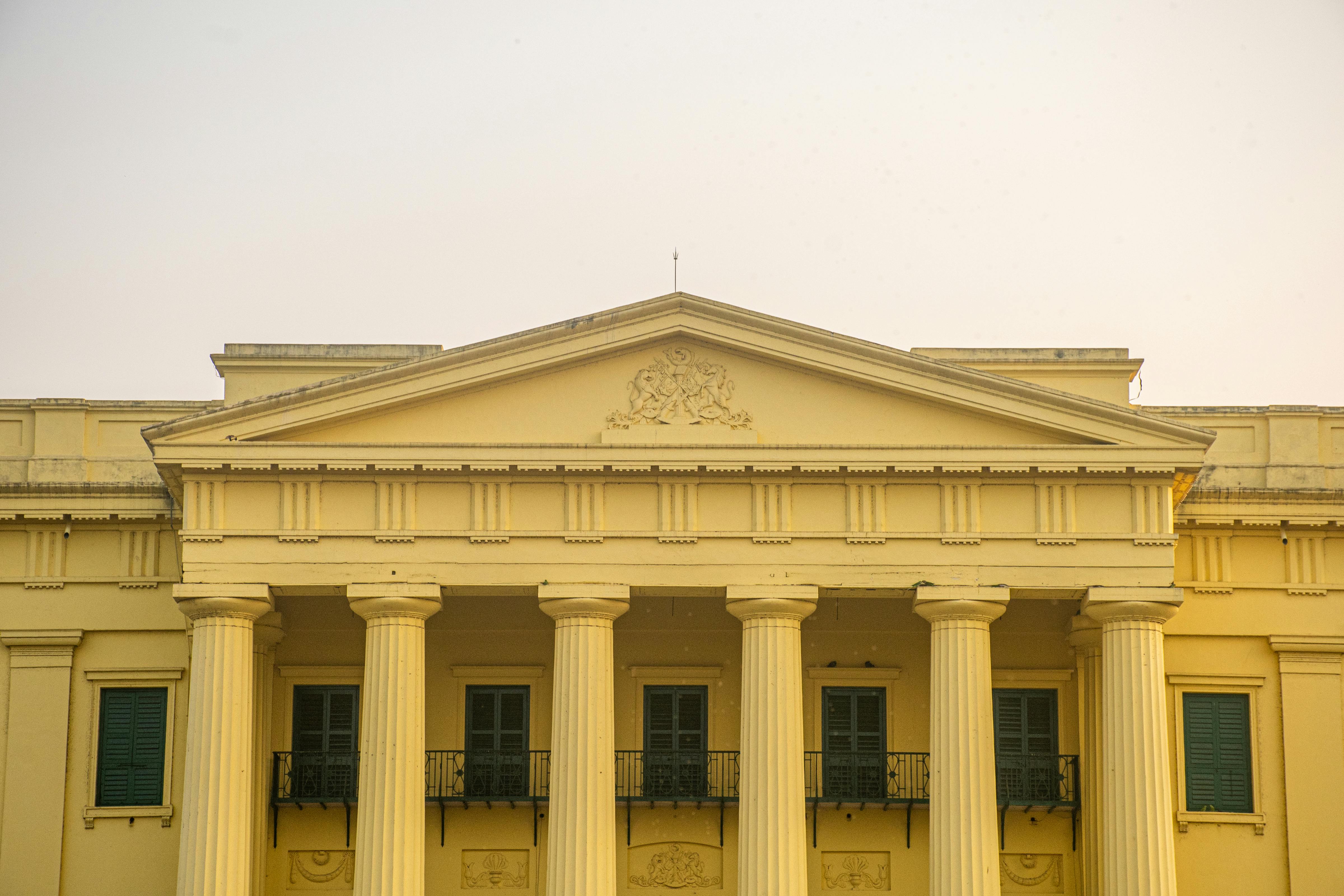 Ilmainen Yksityiskohtainen näkymä uusklassisesta rakennuksen julkisivusta, jossa on näkyvät pylväät ja päätykolmio. Kuvapankkikuva