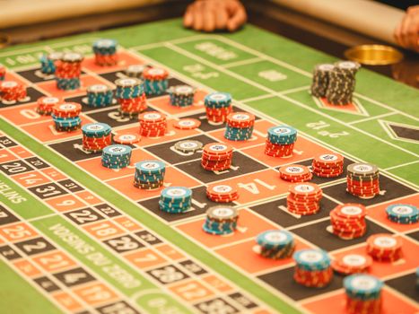 Colorful roulette table with stacks of casino chips in a lively atmosphere.