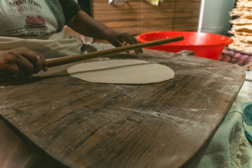 Free A person preparing traditional Turkish flatbread with a rolling pin indoors, showcasing cultural culinary techniques. Stock Photo