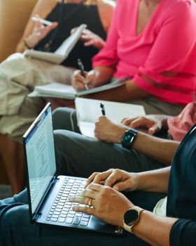 Diverse group of adults collaborating with laptops and notebooks.