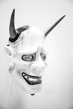 Striking black and white image of a traditional Japanese Hannya mask with intricate details.