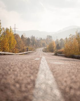 Scenic autumn road with colorful trees and mountains in the distance.