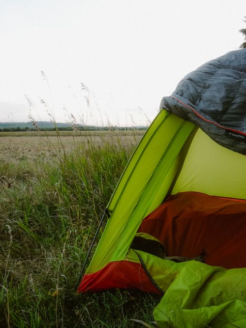 Free Serene camping scene with green tent in a field at dawn, perfect for adventure seekers. Stock Photo