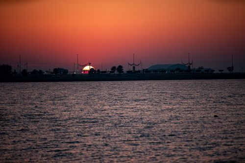 Free Serene sunset over a tranquil waterfront with a silhouette skyline in view. Stock Photo