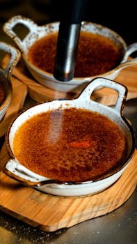 Close-up of creme brulee dessert being caramelized with a torch, served in a rustic dish.