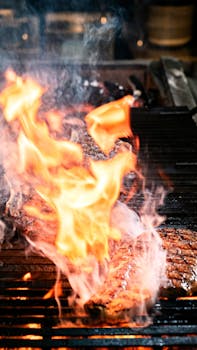 Sizzling steak on a grill with intense flames and smoke in an outdoor setting.