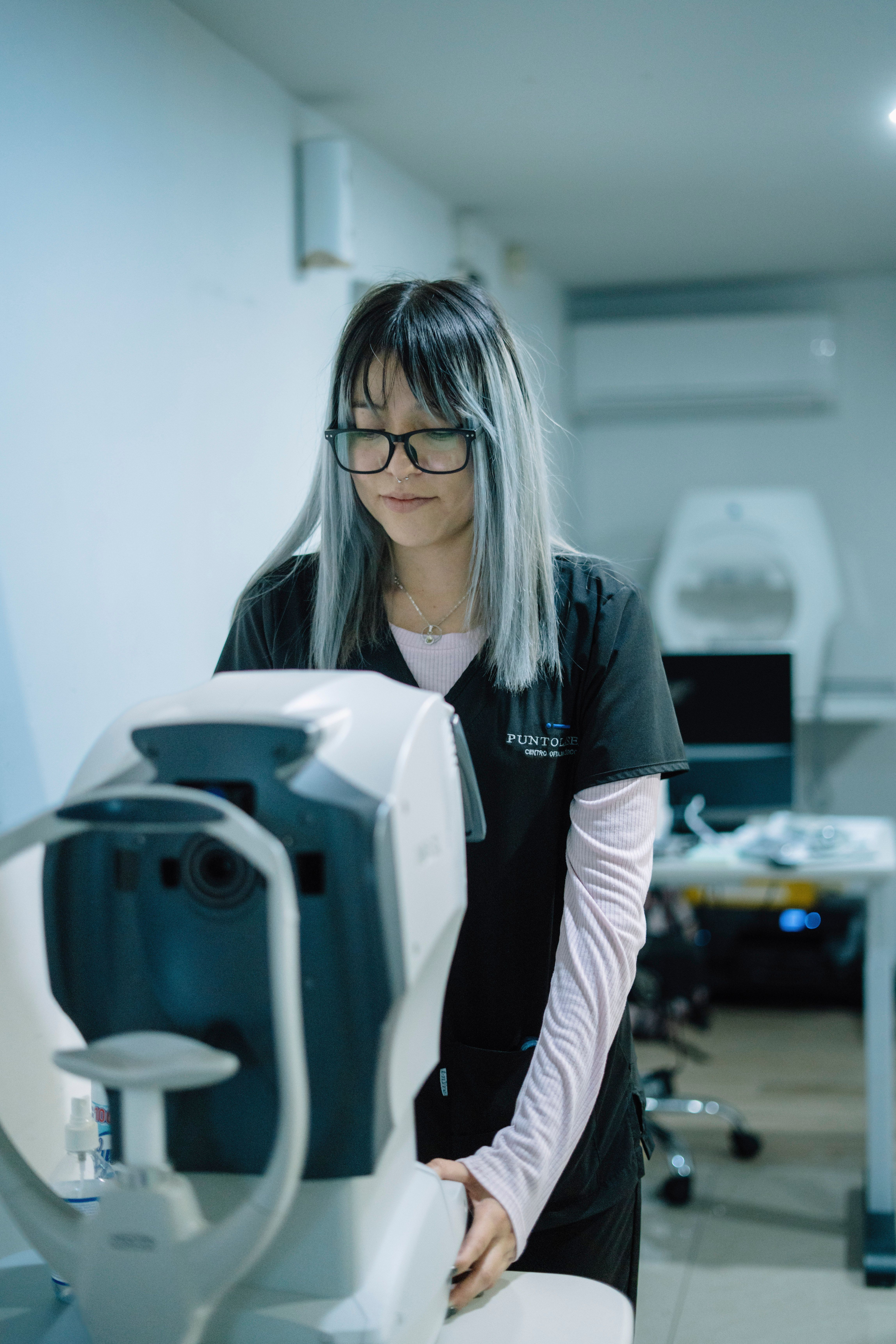 Female optometrist examining patient with modern equipment in a clinic setting.