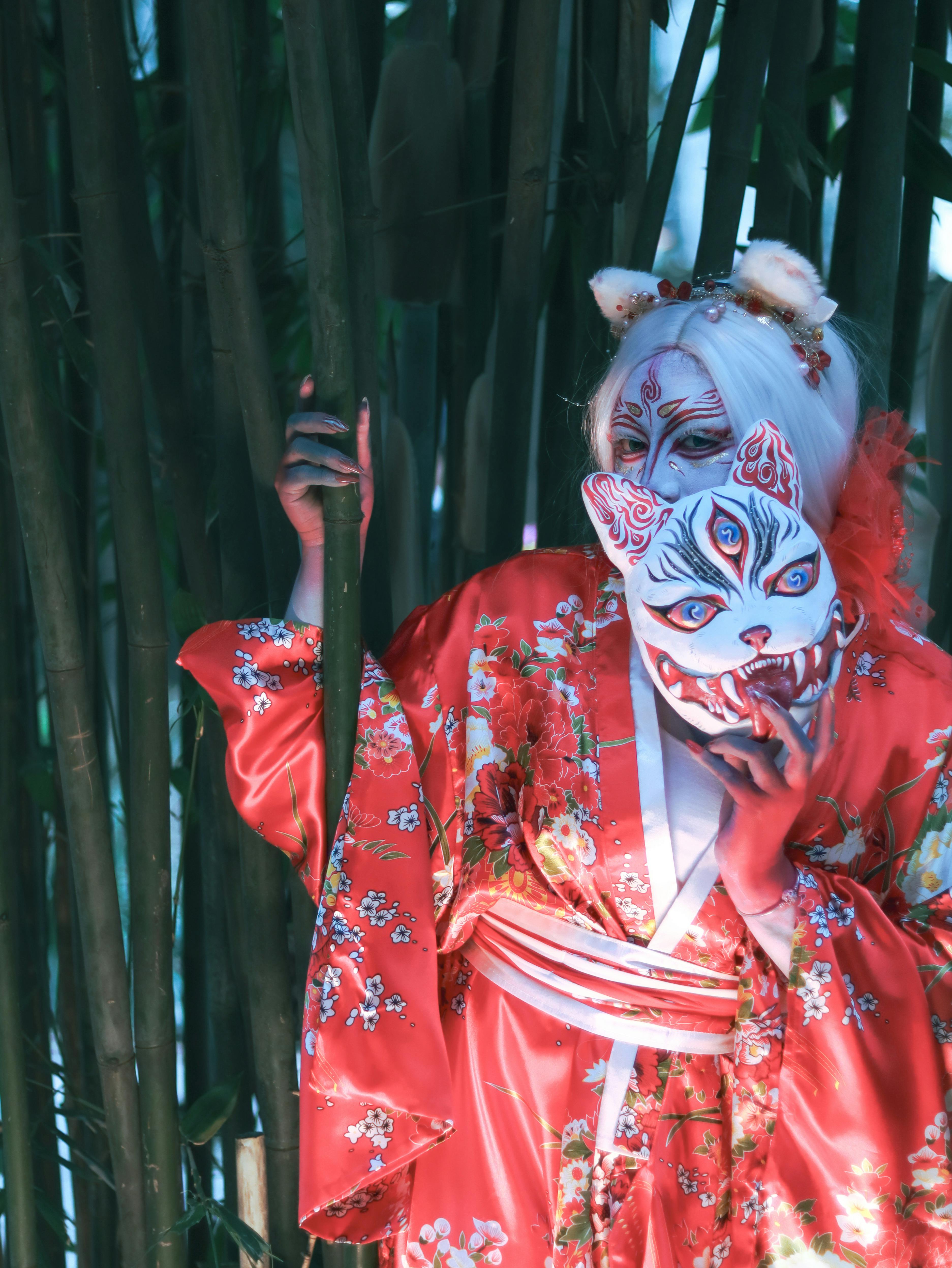 Free Person in a floral kimono and oni mask amid bamboo in Mexico City. Stock Photo