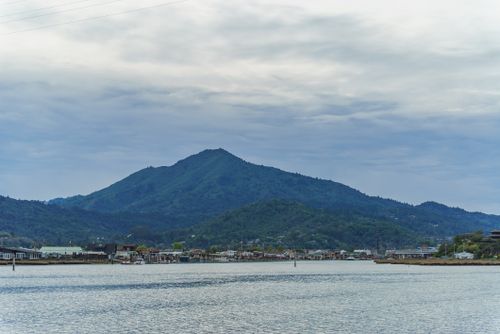 Free A picturesque view of a mountain and village across the water on a cloudy day. Stock Photo
