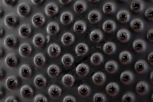 Macro shot of a black textured surface with raised circular patterns and small holes.