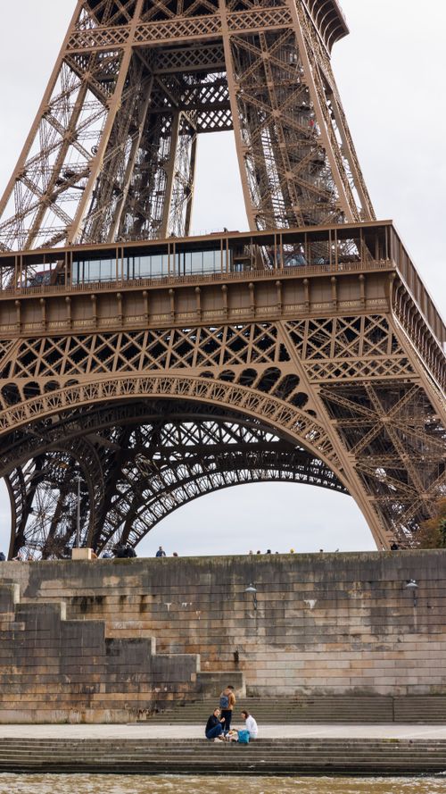 Free View of the Eiffel Tower with people relaxing along the Seine River in Paris. Stock Photo