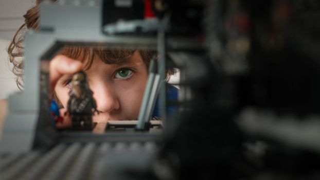 Child with green eye intensely looking through toy figures, exploring creativity and imagination.
