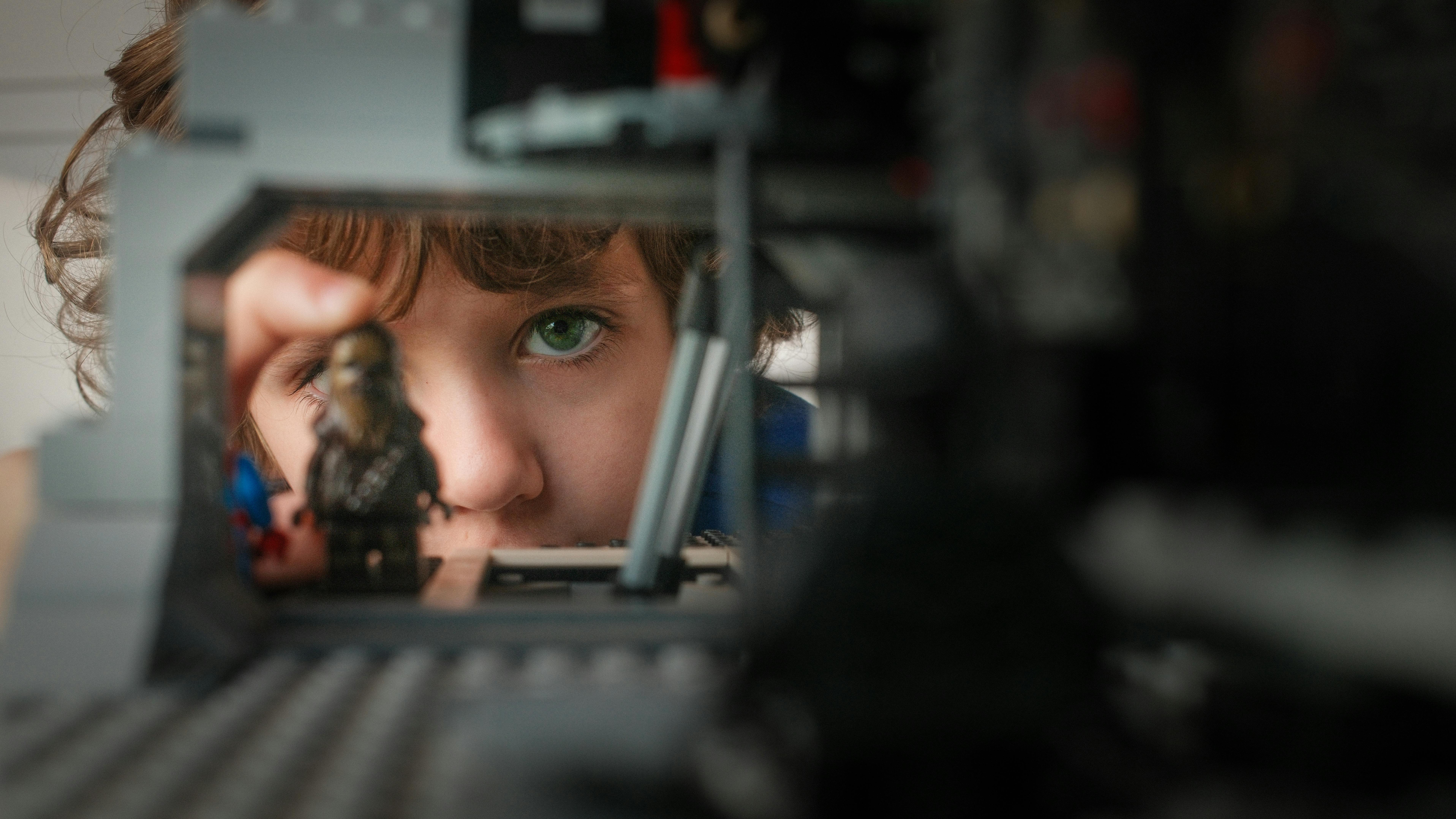 Kostenlos Kind mit grünen Augen betrachtet aufmerksam Spielzeugfiguren und erkundet dabei seine Kreativität und Fantasie. Stock-Foto