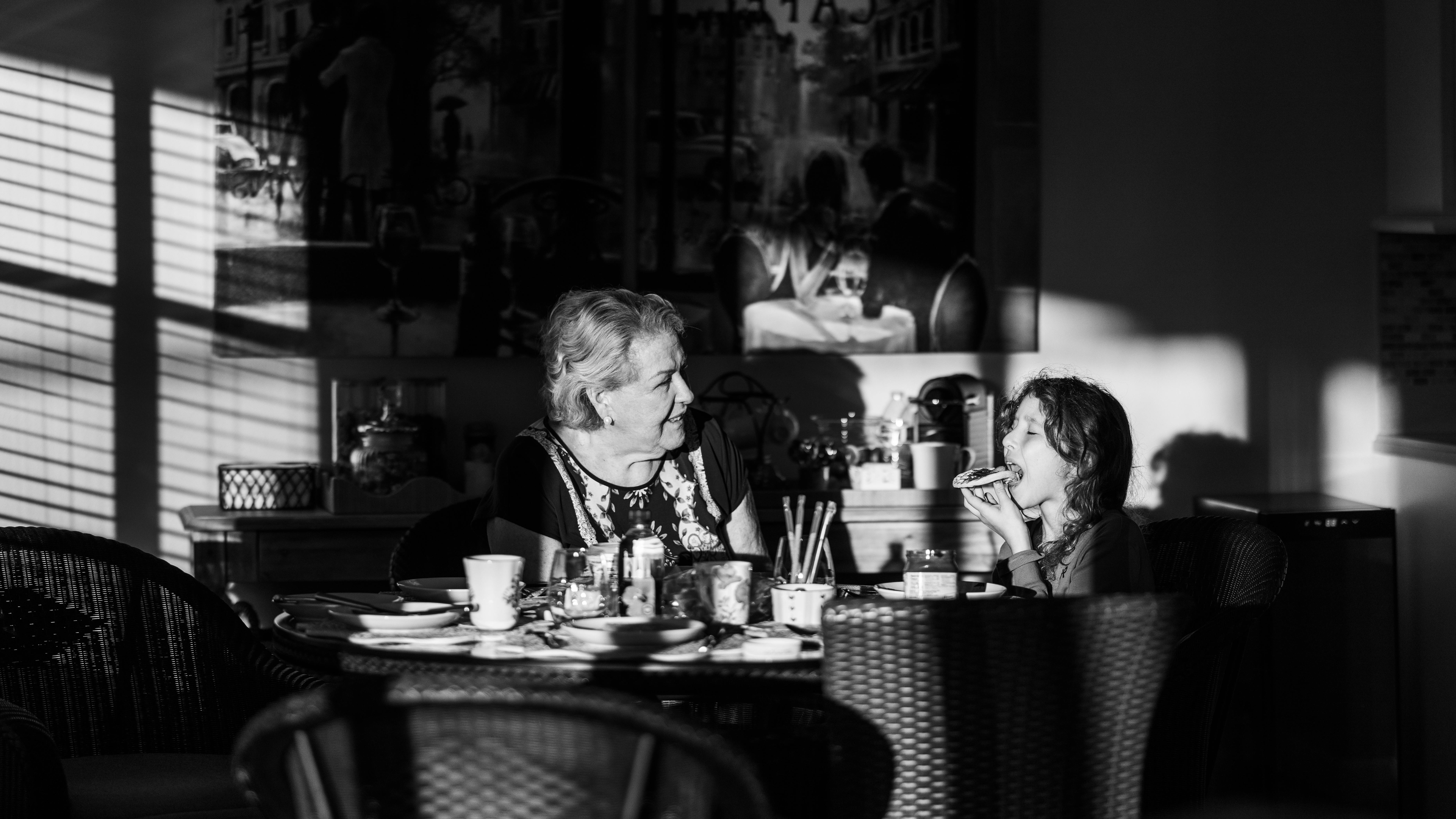 Gratis Seorang nenek dan anaknya menikmati sarapan bersama di bawah cahaya pagi. Mengharukan dan tulus. Foto Stok
