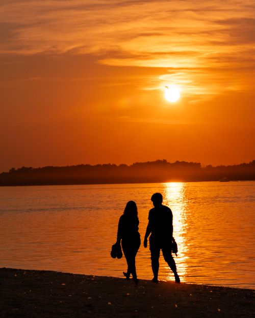 Free Couple silhouetted against a vibrant sunset over the Ottawa River, capturing a moment of tranquility and romance. Stock Photo