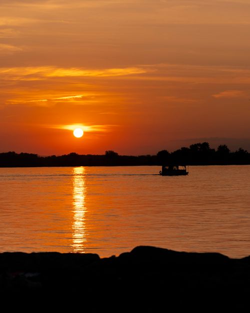 Free Beautiful sunset over Ottawa River with silhouette of a boat on the water, capturing the peaceful ambiance. Stock Photo