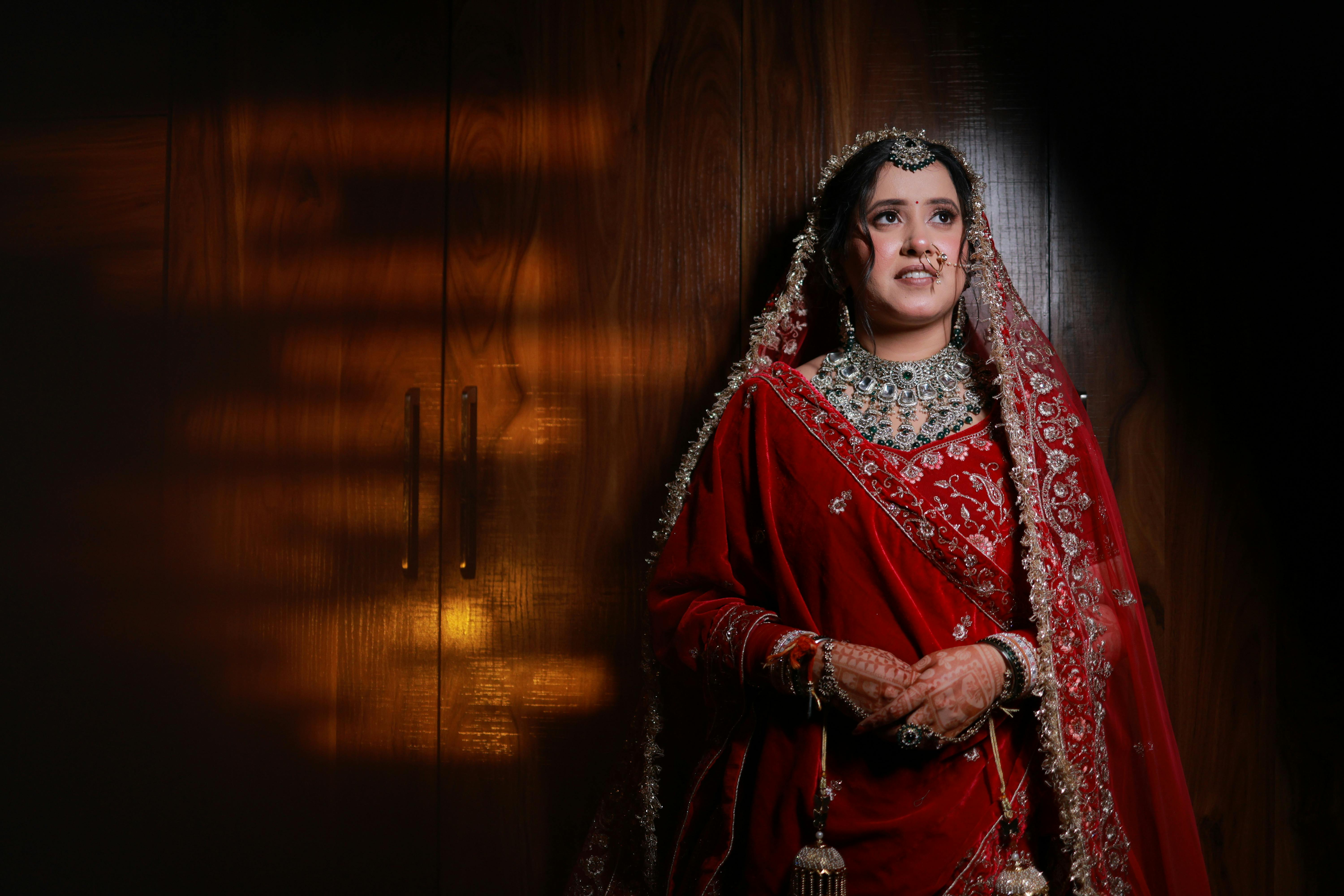 Beautiful Indian bride wearing traditional red attire, showcasing intricate jewelry and henna designs.