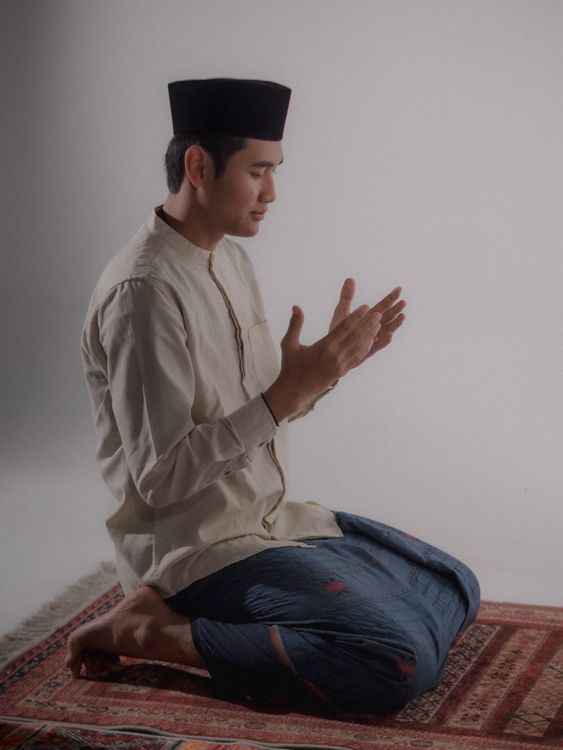 Young Man Praying Indoors in Traditional Attire · Free Stock Photo