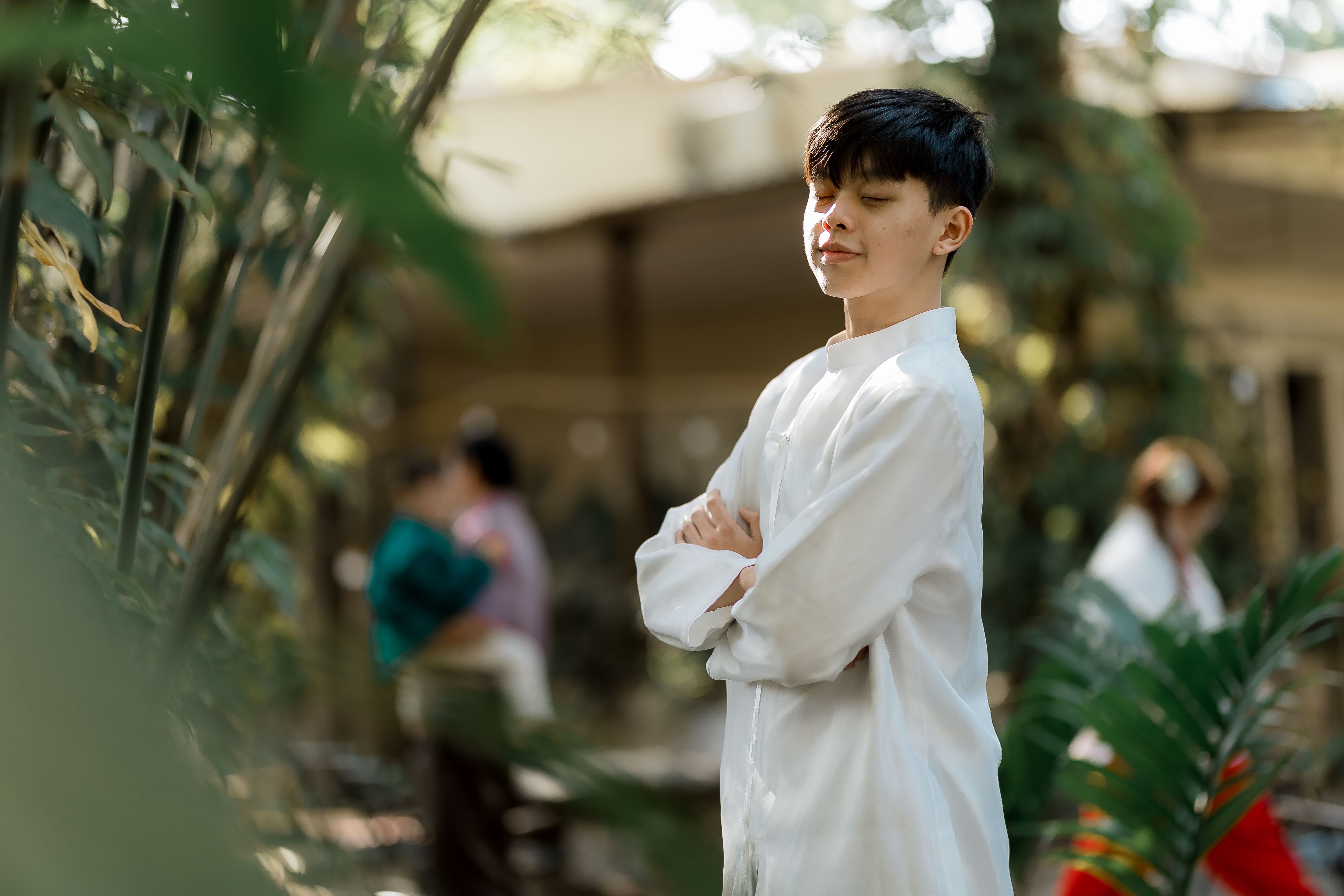 Young man enjoying a peaceful moment in a lush, sunlit garden.
