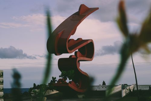 Free Captivating abstract sculpture by the ocean with a cloudy sky backdrop. Stock Photo