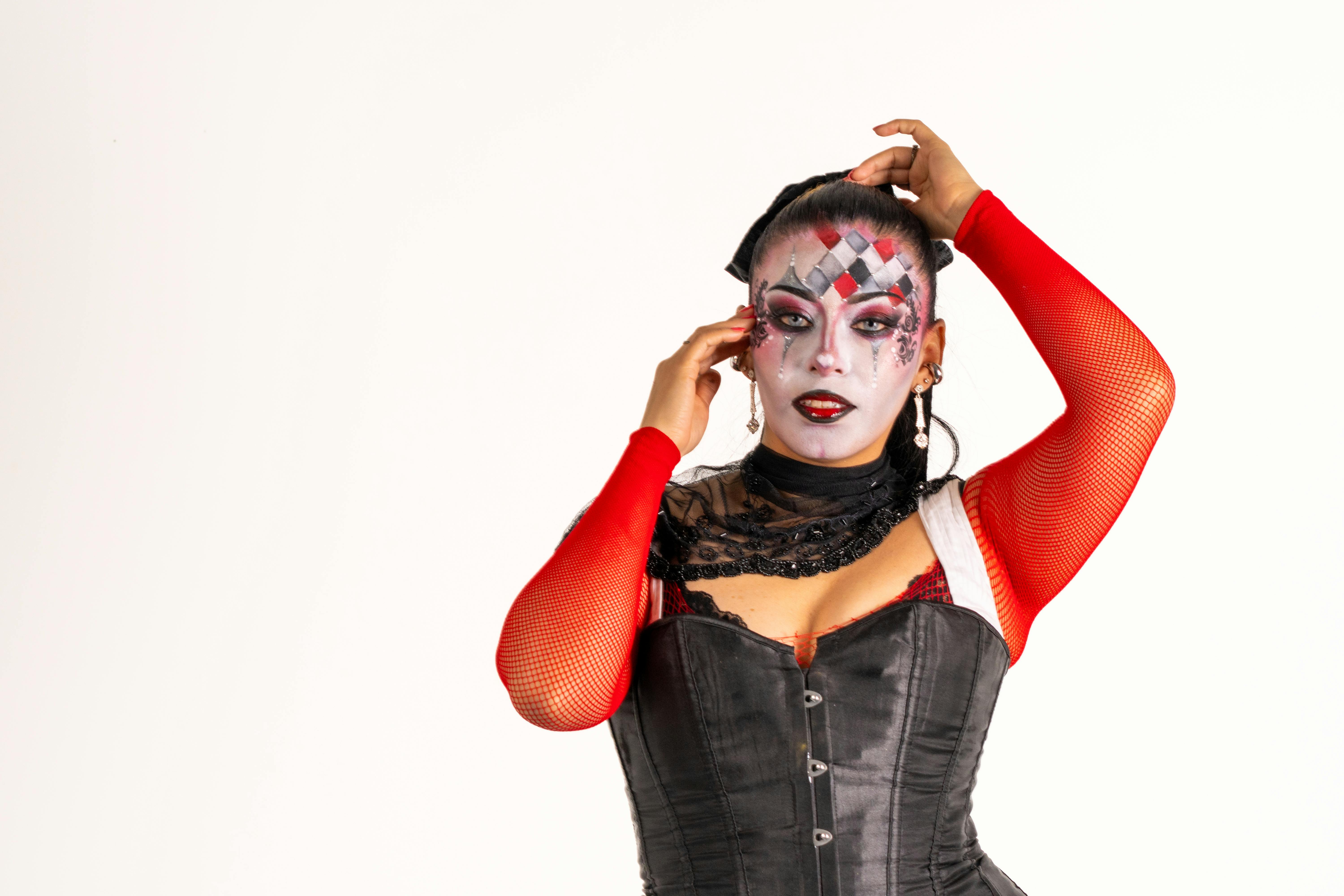 Free Latina woman with creative harlequin-style makeup and costume, showcasing vibrant red and black colors. Stock Photo