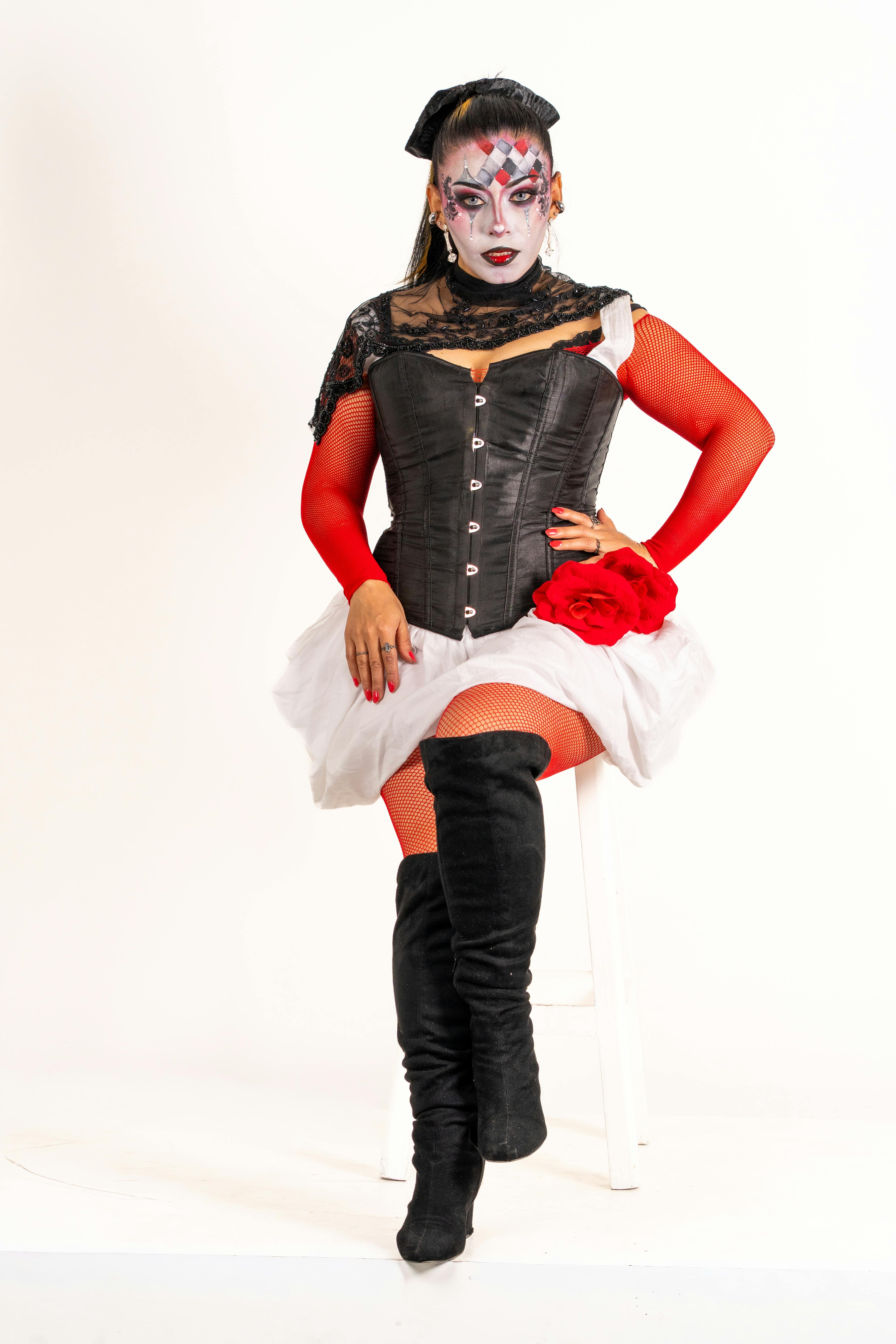 Ilmainen Muotokuva latinalaisameikkisenä ja taiteellisessa pellemeikissä olevasta naisesta istumassa jakkaralla. Kuvapankkikuva