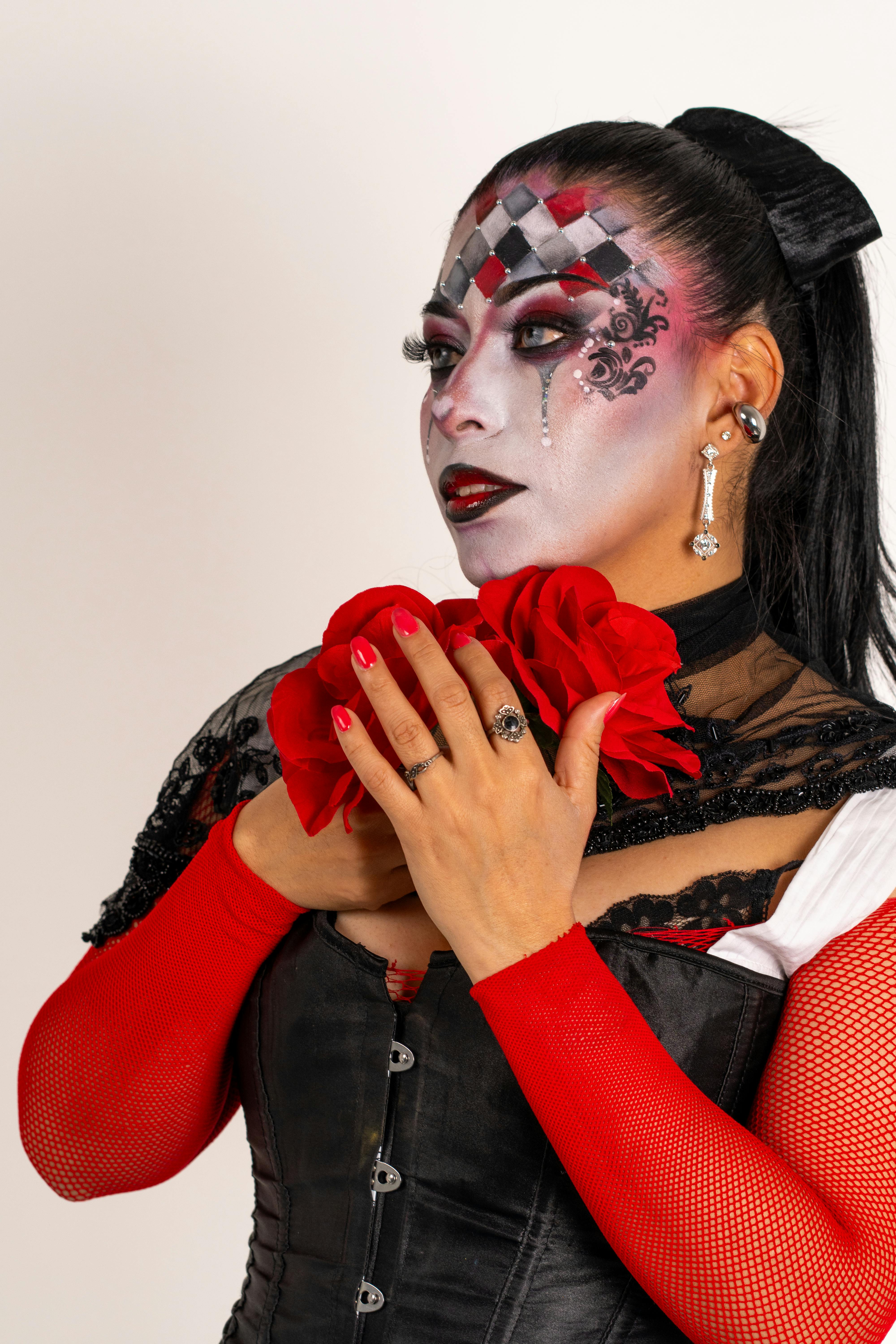 Gratis Seorang wanita Latina dengan riasan badut yang kreatif, aksen merah yang mencolok, dan tatapan dramatis. Foto Stok