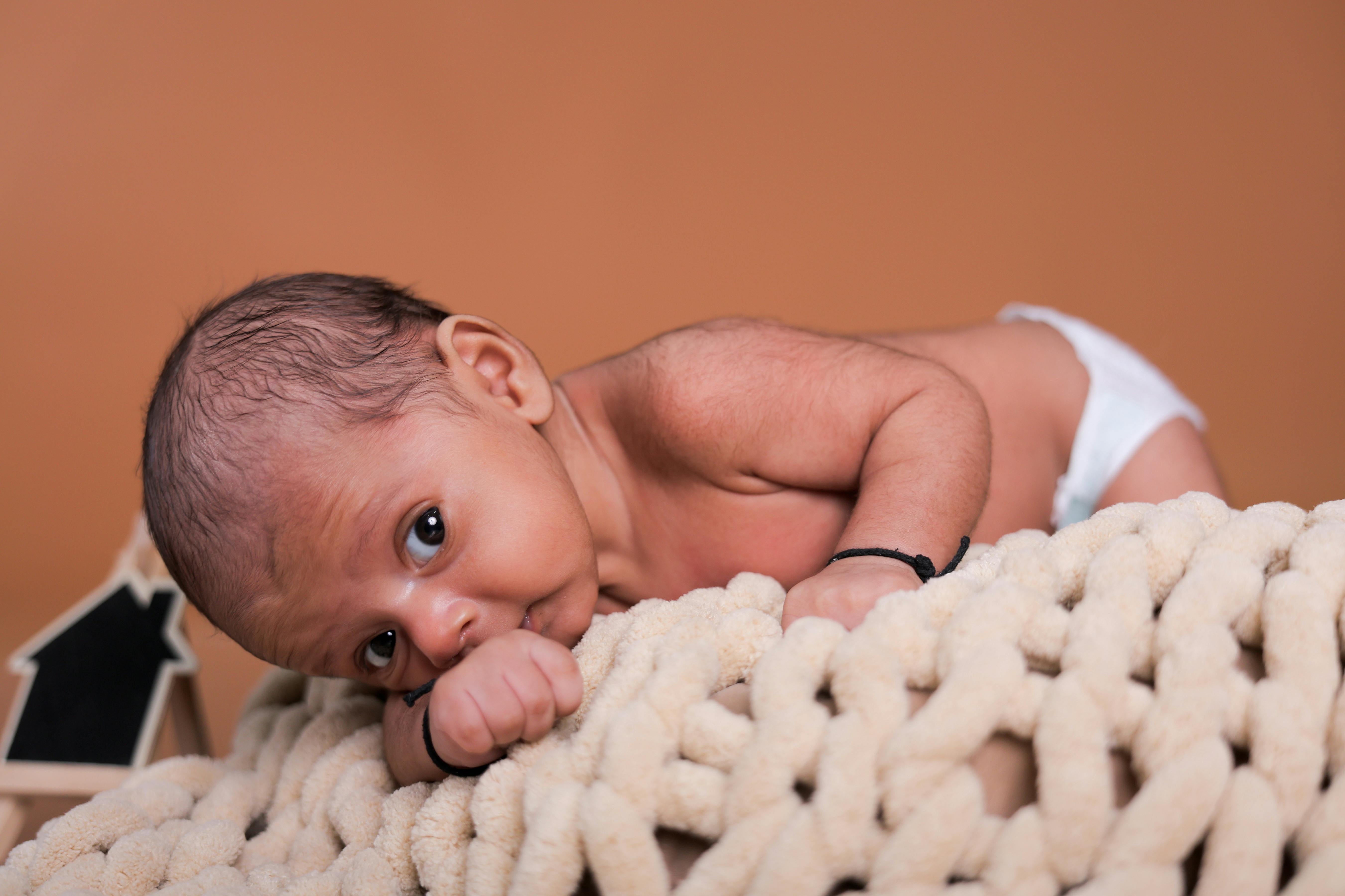Cute newborn baby lying on soft fabric during an indoor photoshoot.