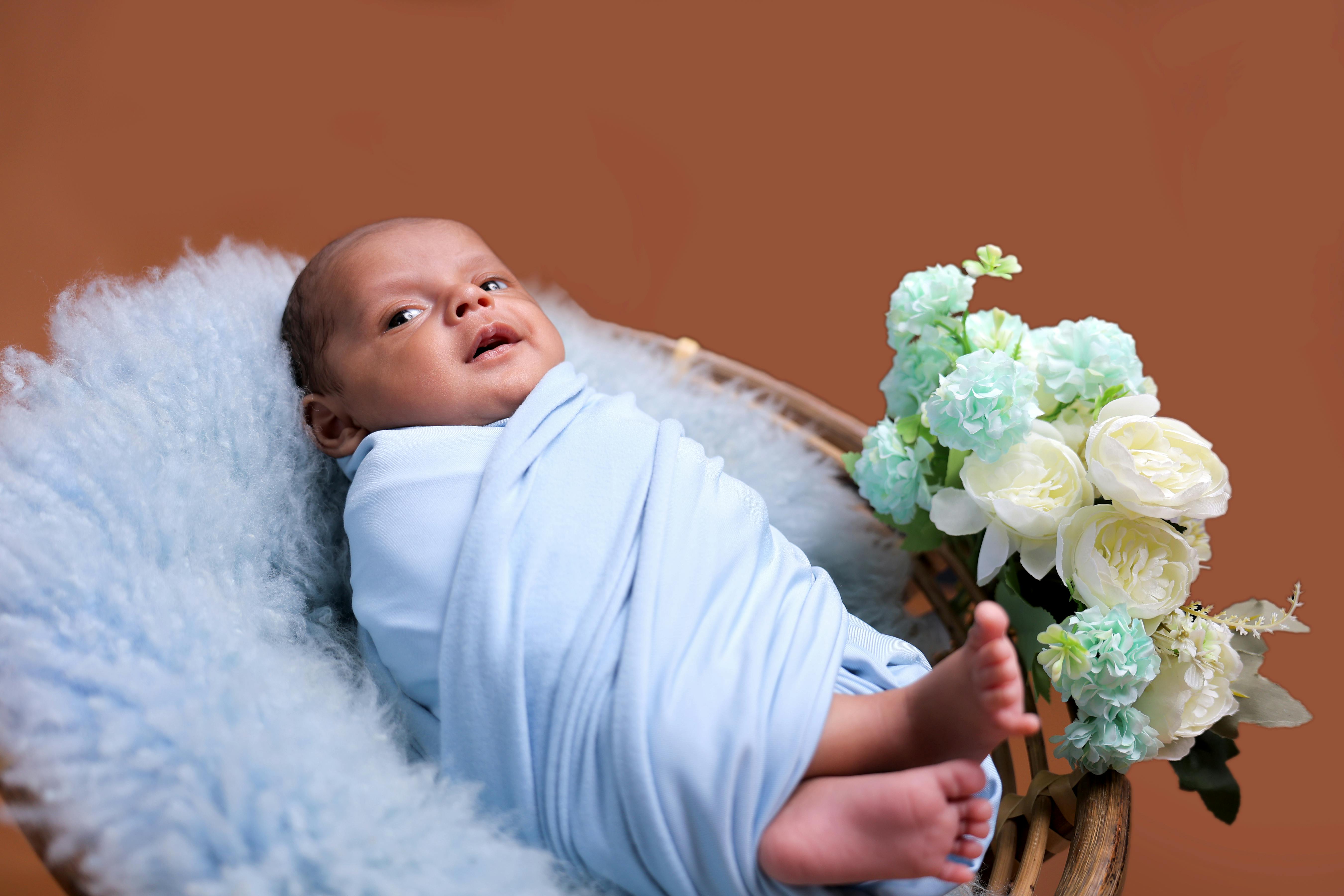 Adorable newborn wrapped in a blue blanket with flowers, perfect for baby-themed designs.