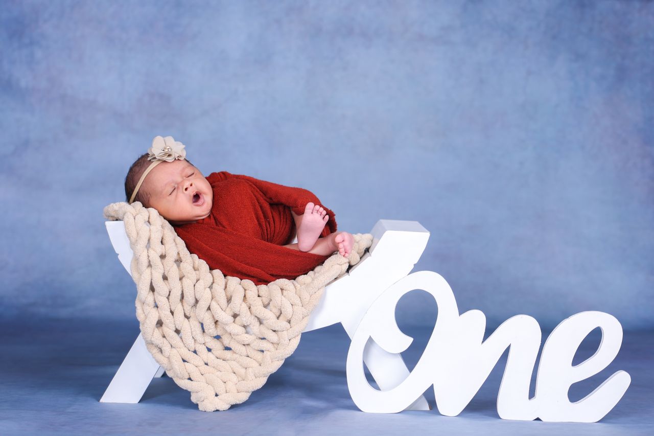 cute newborn in a red outfit on one prop perfect for first birthday ph