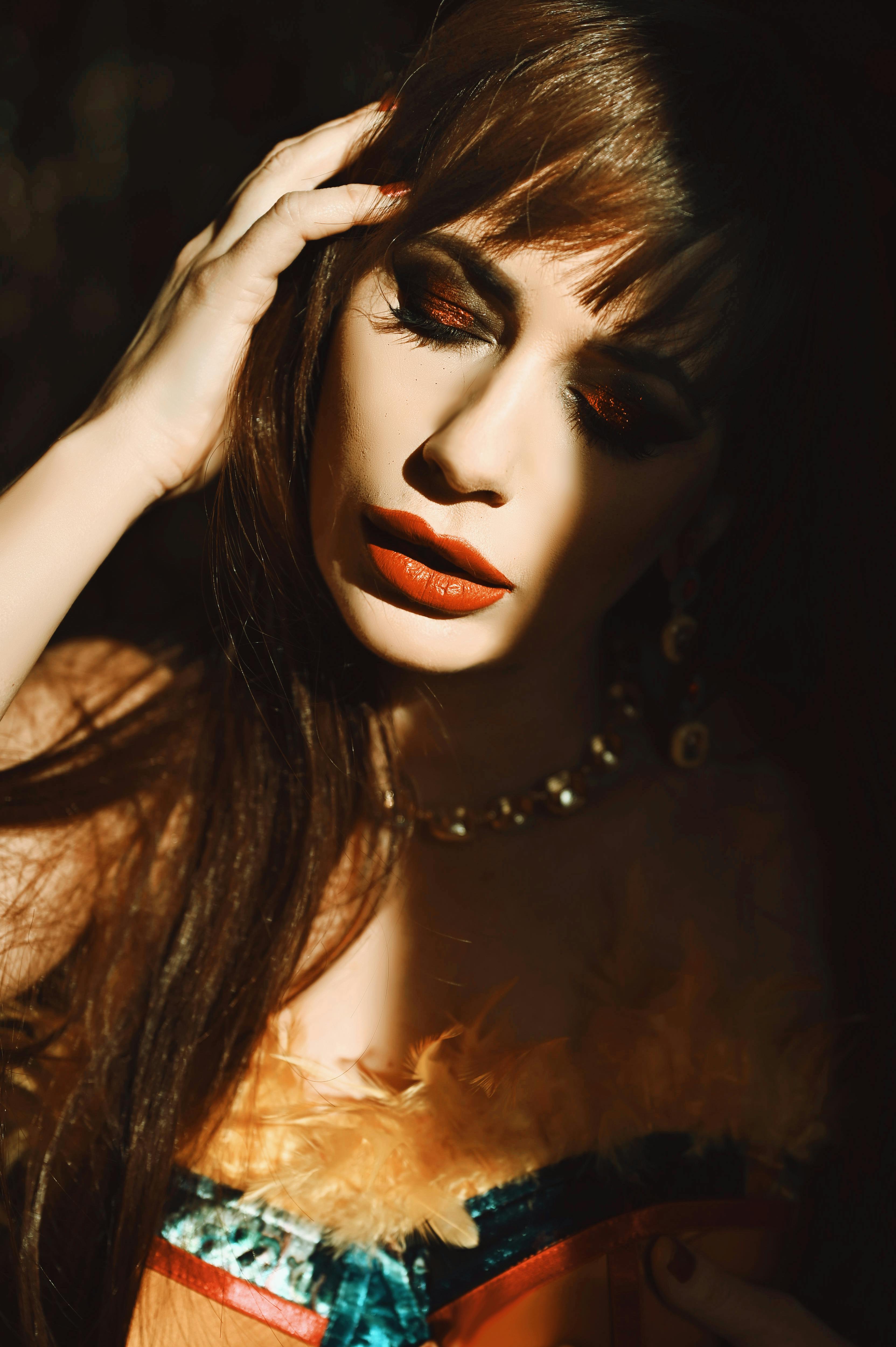 免費 一幅迷人的女性肖像，她化著濃重的妝容，在藝術化的燈光下熠熠生輝。 圖庫相片