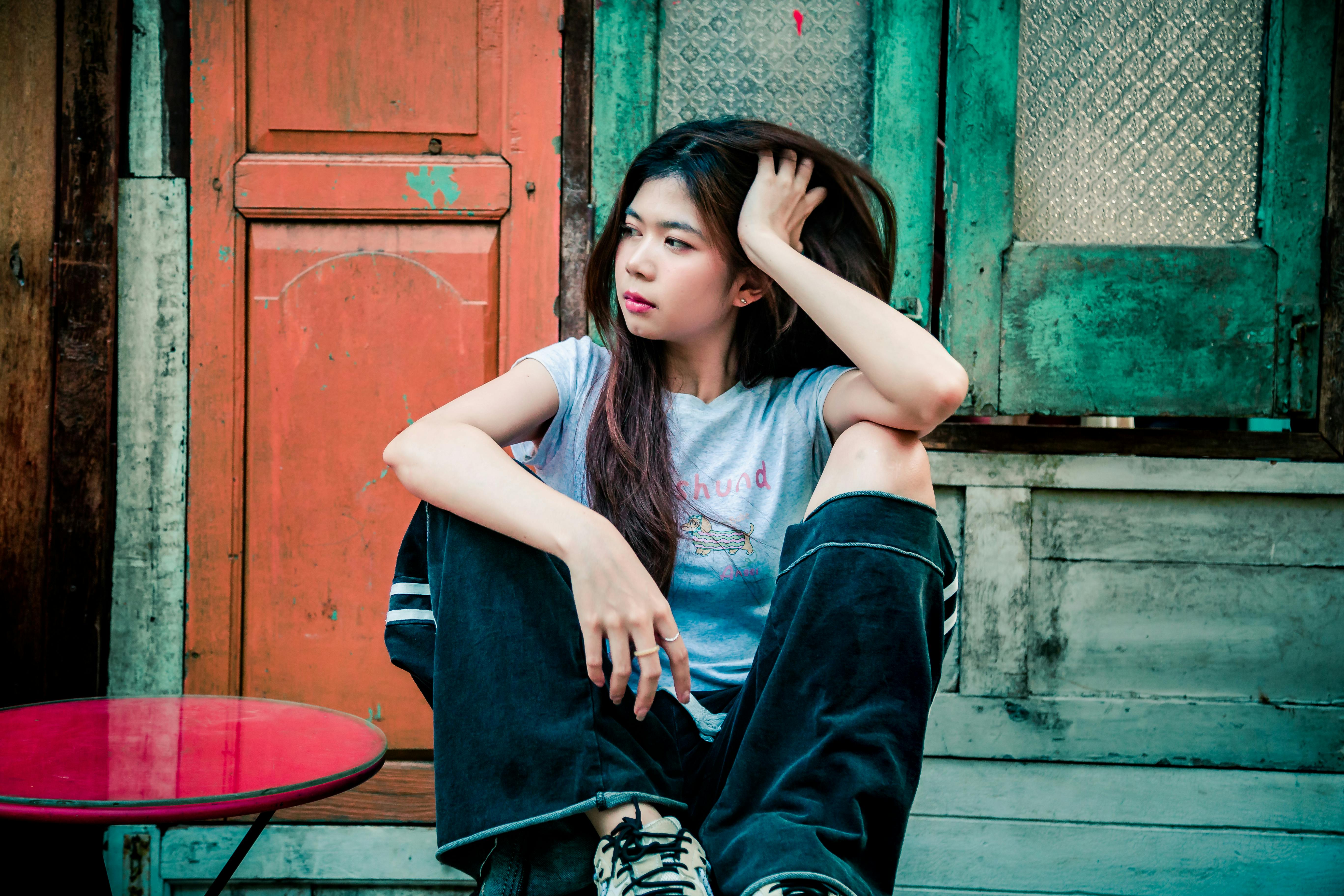 ฟรี หญิงสาวนั่งครุ่นคิดอยู่หน้าฉากหลังแบบวินเทจและเรียบง่าย สื่อถึงความสงบและการใคร่ครวญ คลังภาพถ่าย