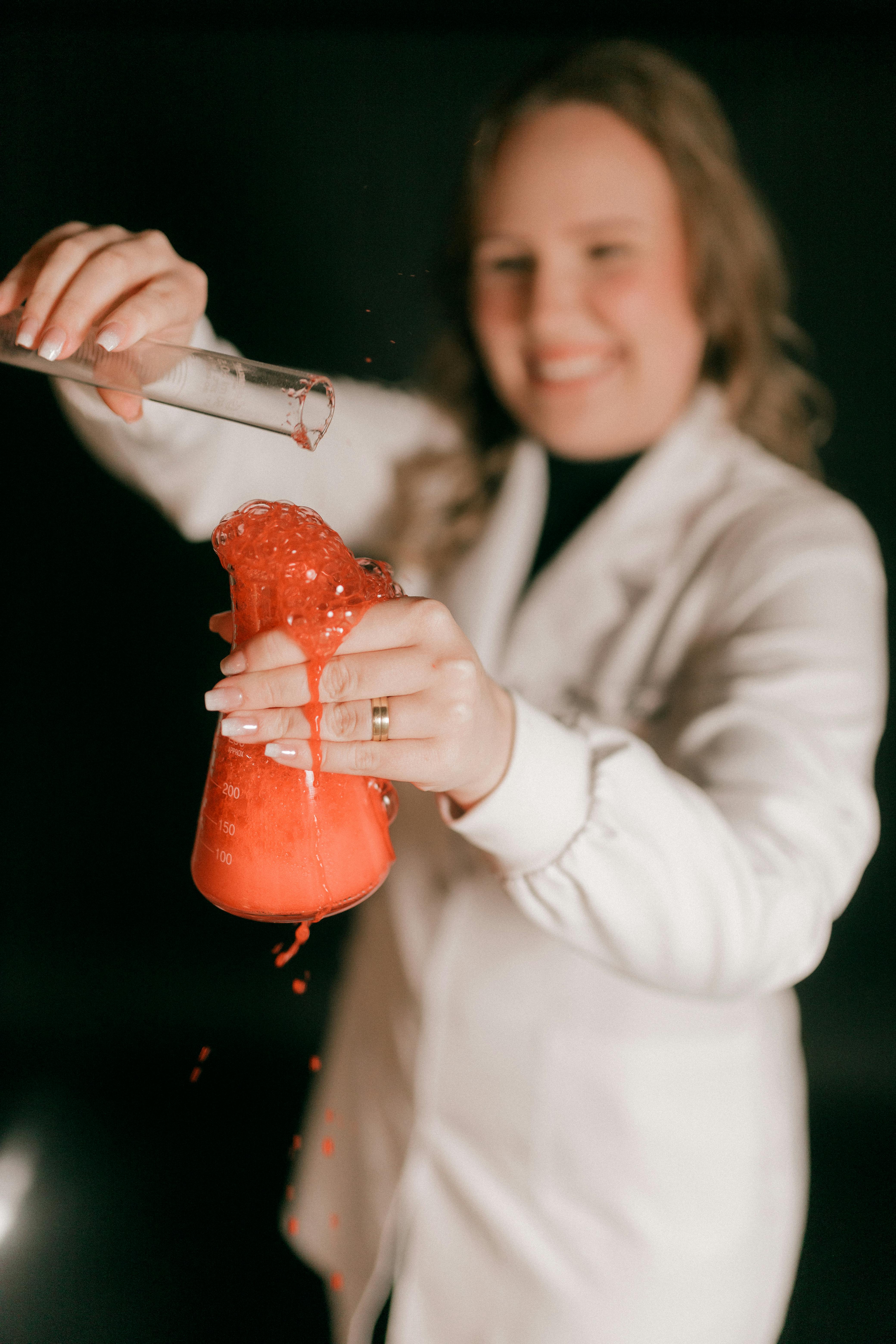 Kostnadsfria Kvinnlig forskare som utför en färgglad kemisk reaktion i ett laboratorium. Stock foto