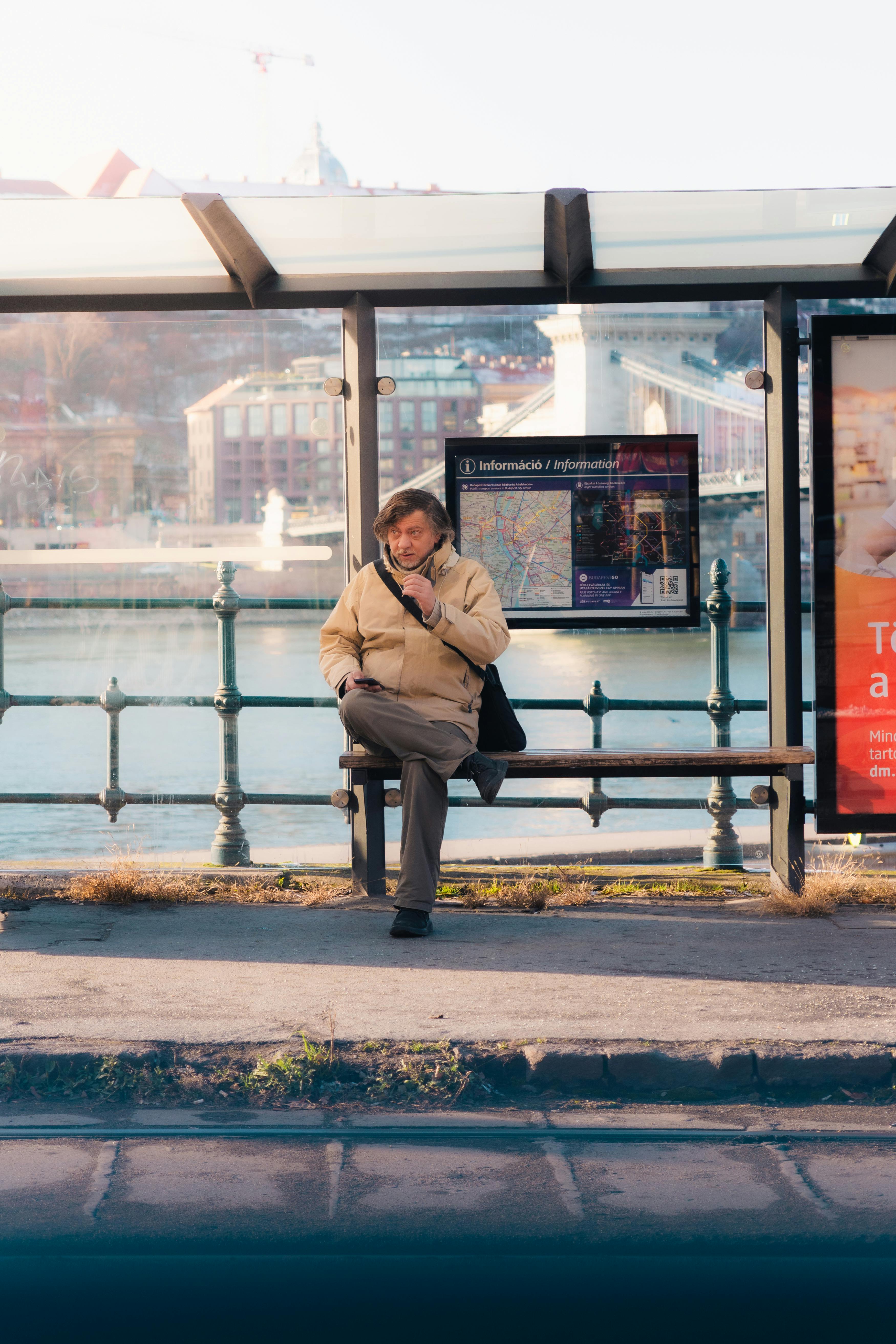 Δωρεάν Ηλικιωμένος άνδρας κάθεται σε σταθμό τραμ στη Βουδαπέστη της Ουγγαρίας, περιμένοντας τα μέσα μαζικής μεταφοράς μια ηλιόλουστη μέρα. Φωτογραφία από στοκ φωτογραφιών