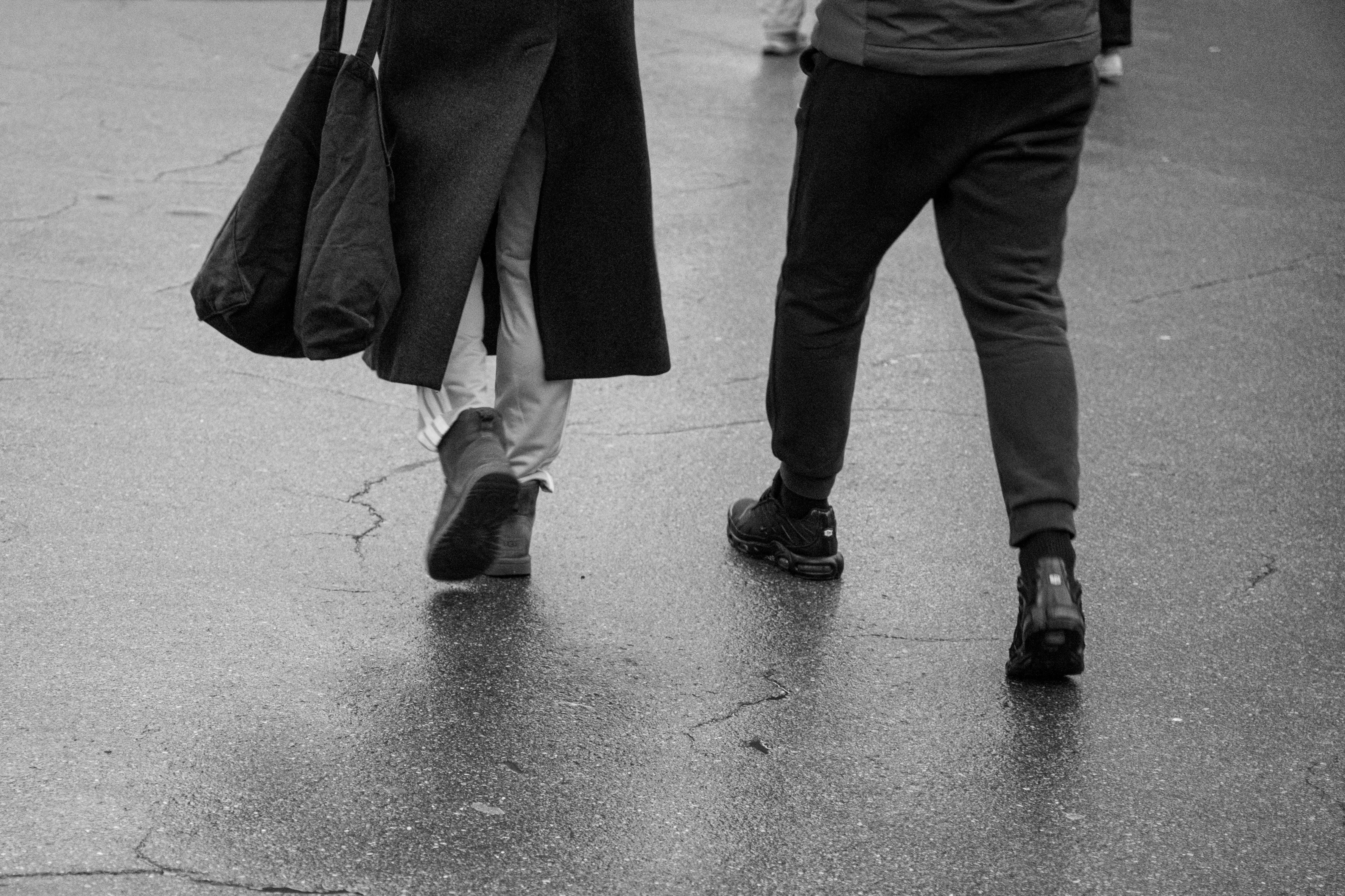 Безкоштовне Елегантне чорно-біле зображення пари, яка йде міським тротуаром, демонструючи міське життя. стокове фото