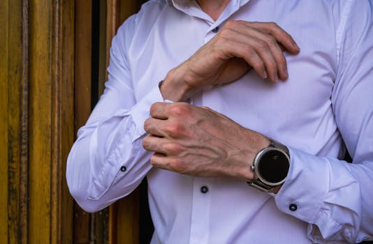 Close-up of a man adjusting his shirt cuff wearing a smartwatch in a stylish setting.
